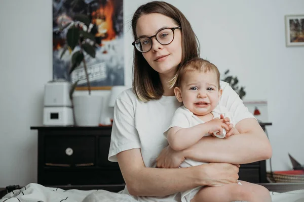 Mamma leker med sin lilla bebis hemma livsstil koncept utseende. Neutrala vita kläder, könsneutrala färger — Stockfoto