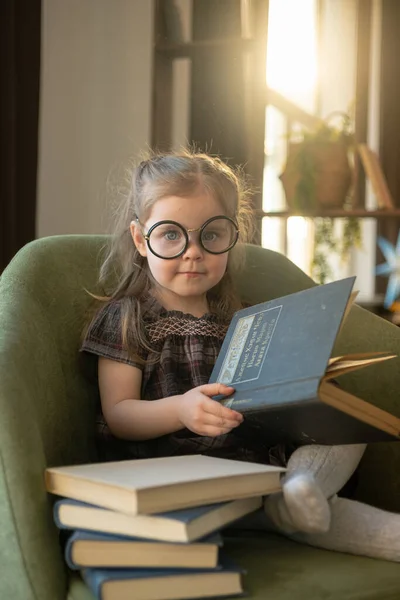 Egy aranyos kislány szemüvegben, aki könyveket olvas. Vissza az iskolába. — Stock Fotó