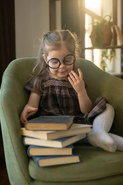 Klein schattig peutermeisje met een bril die boeken leest. terug naar school — Stockfoto