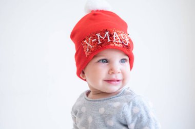 Beyaz monokrom arka planda bebek portresi kırmızı şapkalı, mutlu noeller. Küçük Noel Baba. İyi tatiller.