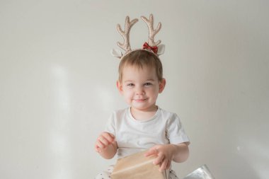 Parlak parlak yağmurlu geyik boynuzları kostümlü küçük kız. Yeni yıl ve noel partisi kutlaması. Noel tatili.