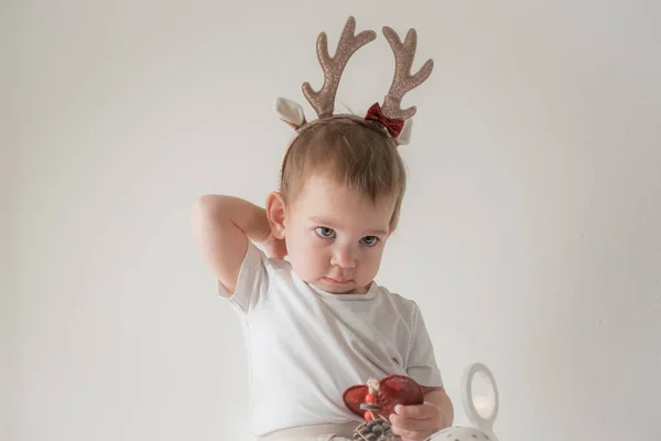 Parlak parlak yağmurlu geyik boynuzları kostümlü küçük kız. Yeni yıl ve noel partisi kutlaması. Noel tatili. — Stok fotoğraf