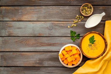 Balkabağı çorbası - maydanozlu ve tohumlu - ahşap arka planda metin için üst görünüm alanı