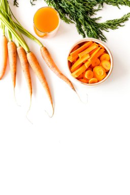 Yeşil kapaklı çiğ havuç ve mutfak masasında taze meyve suyu. Üst görünüm