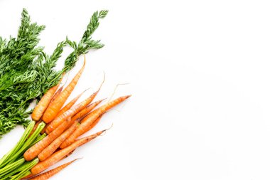 Yeşil kapaklı çiğ havuç ve mutfak masasında yapraklar. Üst görünüm