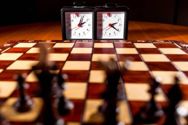 Tahta satranç tahtasının üzerinde saat var.