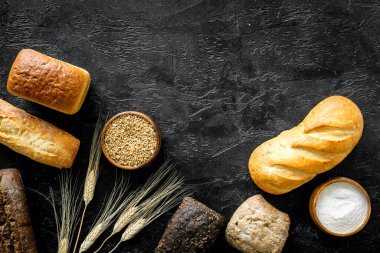 Koyu mutfak masasında buğday kulaklı ev yapımı ekmek. Üst görünüm