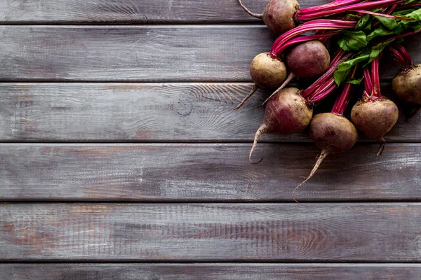 Organic beetroots with green tops and leaves on wooden dark desk. Top view — Stock Photo, Image