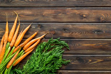 Yeşil kaplamalı organik havuç ve ahşap masasında yapraklar. Üst görünüm