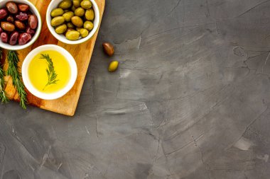 Gri üst görünüm fotokopi alanındaki tahtayı kesen kaplarda zeytin ve zeytin yağı.