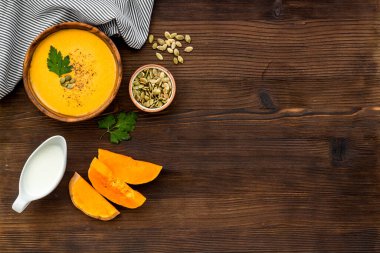 Ahşap masa manzaralı balkabağı çorbası. Kâselerdeki malzemeler. Boşluğu kopyala