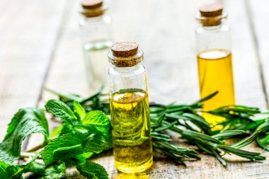 Cam şişelerde bitkisel özü, ahşap masa arkasındaki spa için nane ve biberiye.