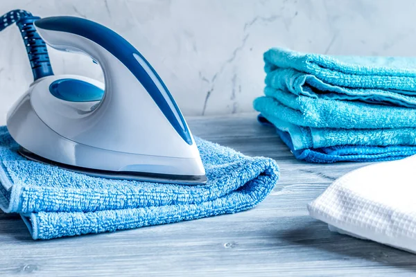Towels pile with iron in housekeeping set on laudry background