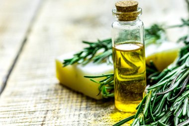 Cam şişelerde bitki özü ve ahşap masa arkasında spa için sabun.
