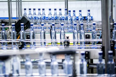 Fabrikada taşıma bandında bir sürü şişe var. Alkol manufaklığı