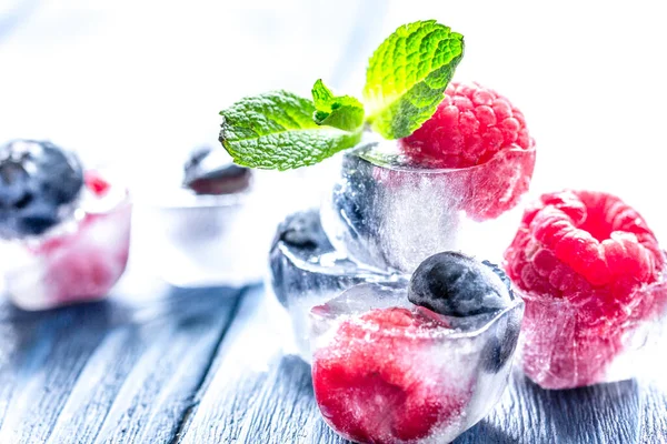 Bayas frescas con menta en cubitos de hielo sobre fondo de madera —  Fotos de Stock