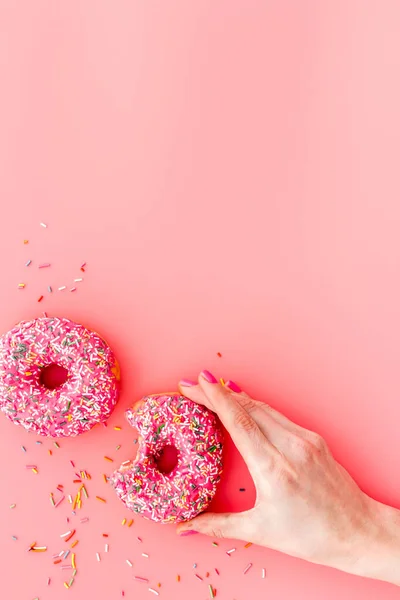 Hand holding donut with icing and sprinkles. Flat lay, top view — Stock Photo, Image