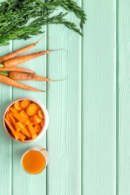 Dilimlenmiş havuç ve meyve suyu yeşil masanın üstünde.