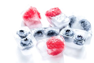 Donmuş yaban mersini ve ahududu buzlu beyaz arka planda