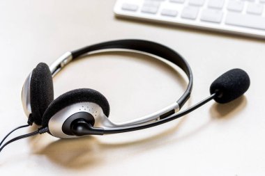 Kulaklık ve klavye kahverengi arka planlı ofis masası