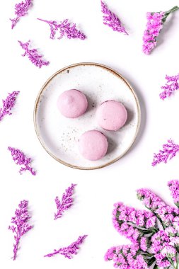 Bayan Morning, badem kurabiyesi ve leylak rengi çiçeklerle beyaz masa arkaplan desenli.