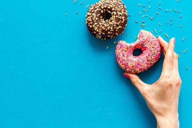 Kremalı ve şekerli donutla el ele tutuşmak. Düz yatış, üst görünüm