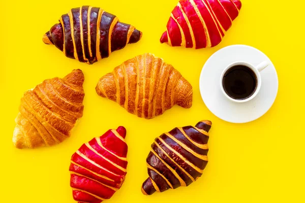 Zestaw kawy z rogalikami - czekoladowe, jagodowe, klasyczne - na żółtym stole — Zdjęcie stockowe