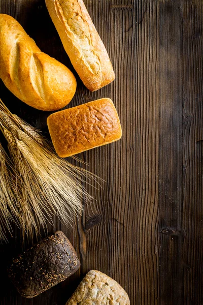 Wholegrain bread near wheat ears on wooden desk from above space for text — Stock Photo, Image