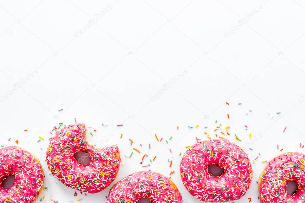 Pink berry donuts flat lay, top view. Glazed and sprinkles doughnuts