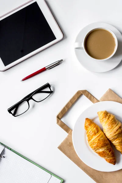 Business lunch with croissant and tablet on white table top view — Stock Photo, Image