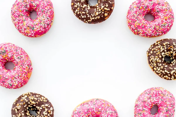 Frame of donuts with icing and sprinkles, overhead view. Colorful bakery — Stock Photo, Image