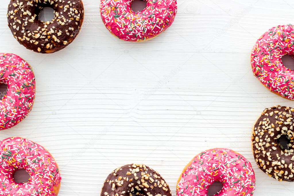 Frame of donuts with icing and sprinkles, overhead view. Colorful bakery