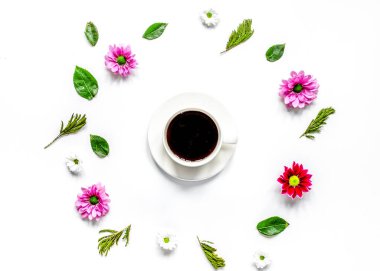 Masa arkasında çiçek yaprakları olan kahve fincanı.