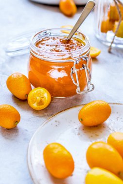 Tabakta kumkat ve gri arka planda kavanoza reçel