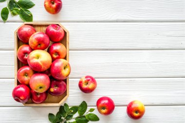 Mutfak masasında yeşil yapraklı kırmızı elmaların üst görüntüsü