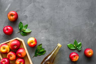 Cam şişede elma sirkesi ve kırmızı elmalı ahşap tepsi.