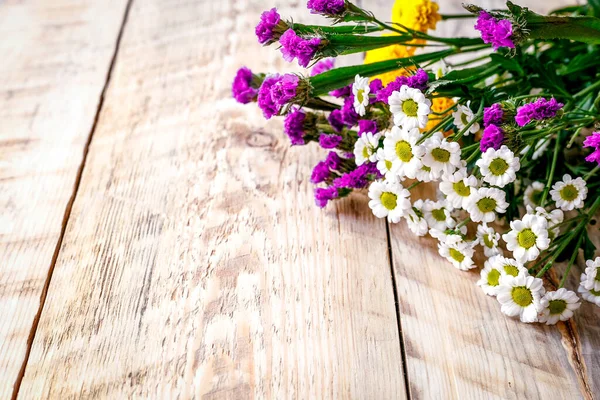 Flores de primavera y manzanillas sobre mesa de madera — Foto de Stock