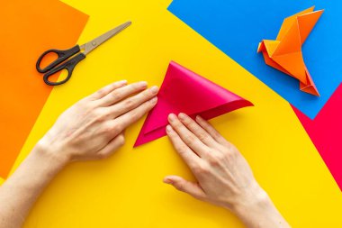 Kağıt katlayan kadın elleri - origami kuşu. Genel Görünüm