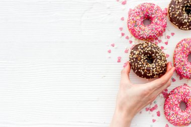 Kremalı ve şekerli donutla el ele tutuşmak. Düz yatış, üst görünüm