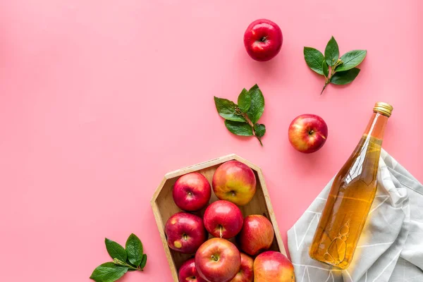 Яблочный уксус в стеклянной бутылке и деревянный поднос с красными яблоками — стоковое фото