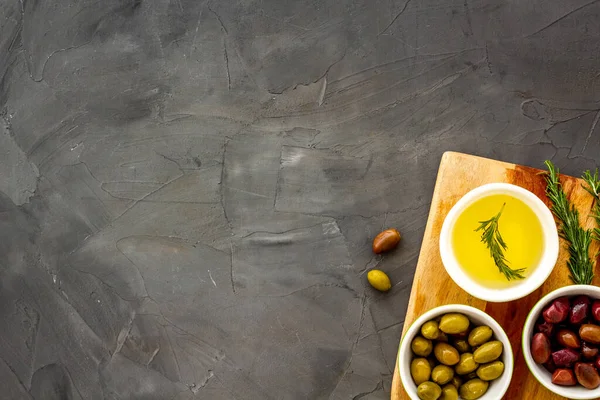 Aceitunas verdes y negras, aceite de oliva en cuencos en la tabla de cortar espacio de copia de arriba hacia abajo —  Fotos de Stock