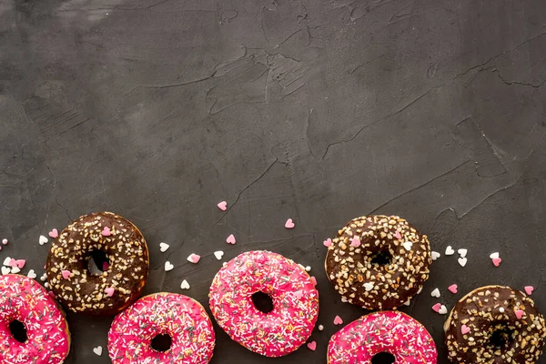 Donuts flat lay pattern on dark background, top view — Stock Photo, Image