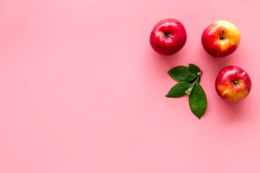 Mutfak masasında yeşil yapraklı kırmızı elmaların üst görüntüsü