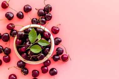 Tahta kasede yaprakları olan kırmızı kirazlar. Düzen, böğürtlen arka planı