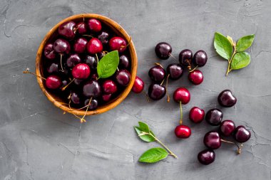 Tahta kasede yaprakları olan kırmızı kirazlar. Düzen, böğürtlen arka planı