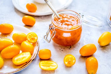 Tabakta kumkat ve gri arka planda kavanoza reçel