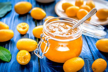 Tabakta kumkat ve kavanozda reçel ahşap masada.