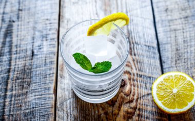 Buzlu ve limonlu bardak, ahşap masada nane.