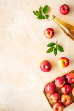 Cam şişede elma sirkesi ve kırmızı elmalı ahşap tepsi.