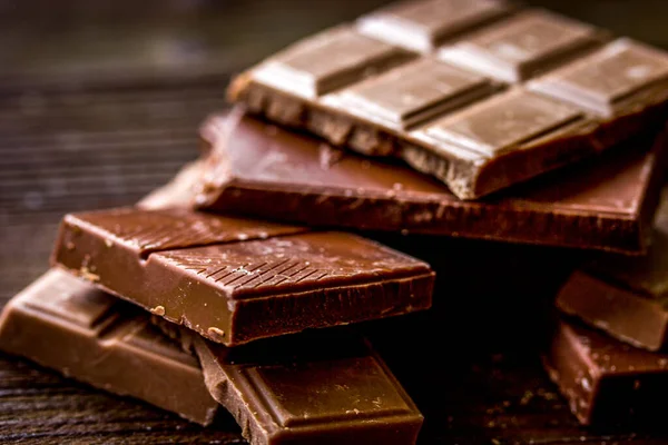 Černé a mléčné čokolády tyčinky tmavý dřevěný stůl pozadí — Stock fotografie